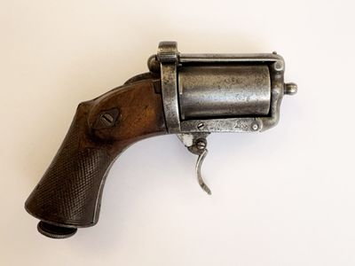 un vieux pistolet avec une poignée en bois sur une surface blanche