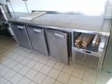 une cuisine équipée d'un plan de travail en inox et de deux réfrigérateurs