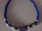 un gros plan d'un collier bleu orné de perles argentées posé sur une table