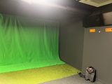 a green screen in the corner of a room with a backpack