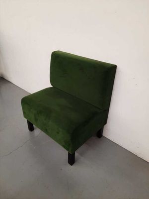une chaise verte contre un mur blanc dans une pièce vide