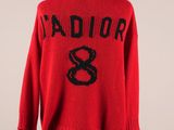un pull rouge avec des lettres noires et un serpent dessiné dessus