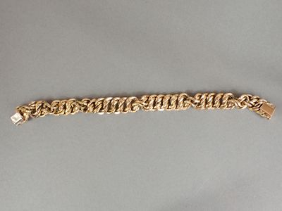 gros plan d'un bracelet en chaîne en or sur une surface grise