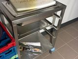 a pizza sitting on top of a metal cart in a kitchen