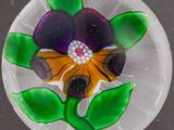 une plaque de verre sur laquelle est représentée une fleur violette et jaune