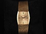 a close up of a gold wrist watch on a black cushion