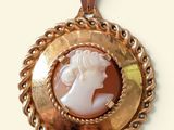 an image of a picture of a woman ' s face in a gold pendant