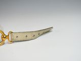 a leather keychain with a gold ring on a white table