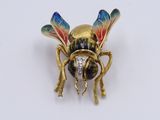 an image of a gold and enamel insect broochle on a white surface