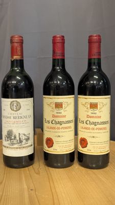 three bottles of wine sit on a wooden table in front of a gray wall
