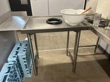 une table en acier inoxydable sur laquelle est posé un saladier contenant de la nourriture