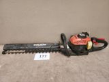 une taille-haie Black & Decker posée par terre près d'un mur