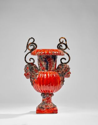 un vase orange posé sur une table près d'un mur blanc