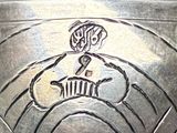 a close up of a silver bowl with a design on it