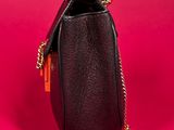 a small black purse with a gold chain hanging from it