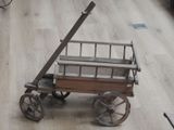 un petit chariot en bois muni d'une poignée en métal et d'un plancher en bois