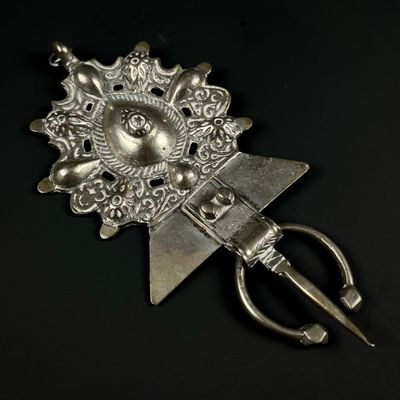 une petite broche en argent ornée d'un oiseau et d'une paire de ciseaux au milieu