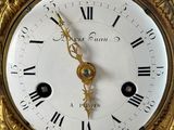 a gold clock with roman numerals on the face