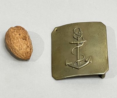 a metal buckle with an anchor on it next to a nut
