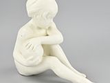 a white figurine of a boy sitting on the ground
