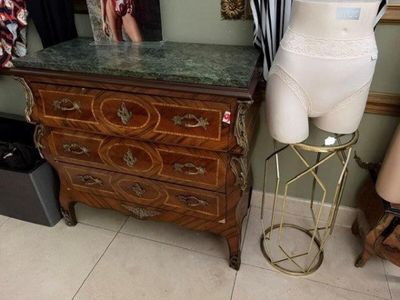 un mannequin posé sur un socle à côté d'une commode