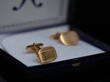 gold plated cufflinks in a gift box with a black background