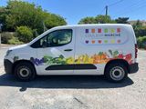 the van is parked on the side of the road with a lot of fruit on it