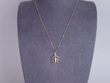 a gold necklace with a cross pendant on a mannequin neck