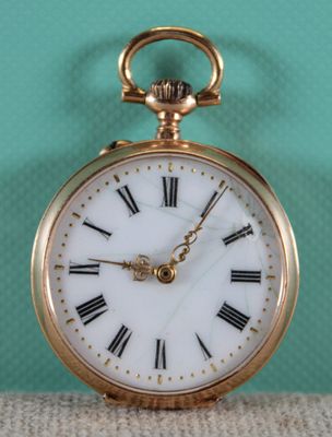 a gold pocket watch with roman numerals on the face