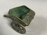 an antique brass carriage with a green seat on a white surface