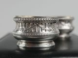 two silver bowls sitting on top of a black table