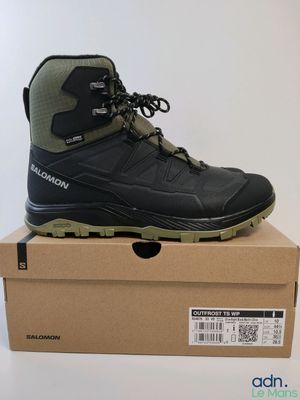 une paire de chaussures de randonnée noires posée sur une boîte en carton