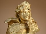 bronze bust of a young boy with long hair and a hat