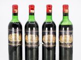 four bottles of wine are lined up on a white surface
