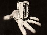 une photo en noir et blanc d'une main tenant une maquette de bâtiment