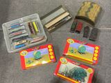 une boîte de crayons, de stylos et une boîte de gommes posées par terre