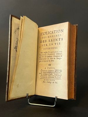 an old book opened to reveal a page of text on a black surface