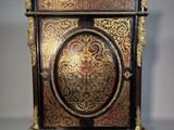 une image représentant une armoire peinte en noir et or, surmontée d'une horloge