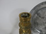 a silver plate and a gold candle holder on a table