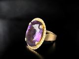 a close up of a gold ring with a purple stone
