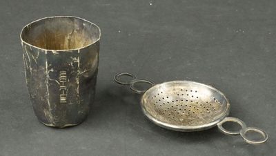 silver cup and strainer on a black background