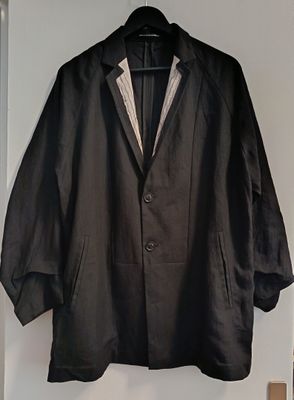 a black jacket hanging on a wall next to a coat rack