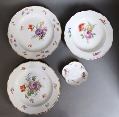 quatre pièces de vaisselle en porcelaine ornées de fleurs, posées sur une table