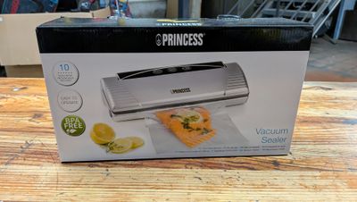 La boîte est ouverte sur une table ; elle contient un sandwich et un coupe-citron.