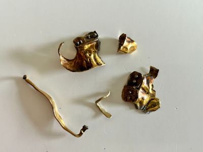 three pieces of gold on a white surface