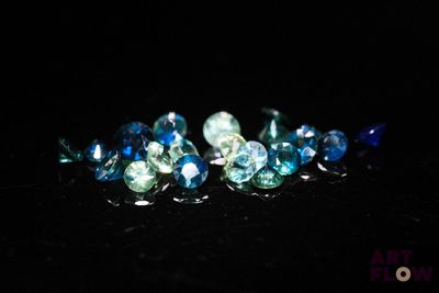 some blue and green crystals are sitting on a black surface