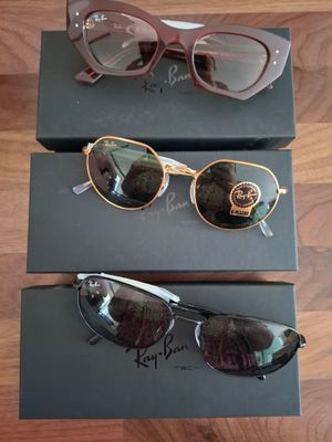 deux paires de lunettes de soleil sont posées sur une boîte, sur un plancher en bois