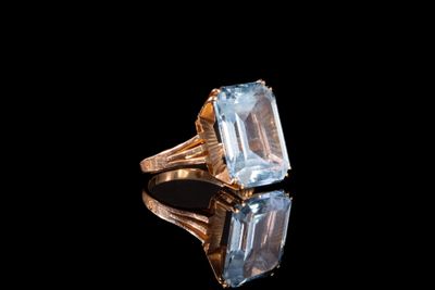 un gros plan d'une bague sertie d'une aigue-marine sur un fond noir