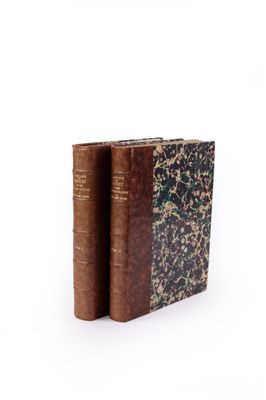 two old books sitting on top of each other on a white surface
