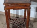 a small wooden table with a glass top on a tiled floor